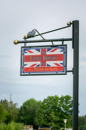 a sign for the little britannian inn on a pole at The Little Britain Inn Themed Hotel One of a Kind In Europe in Vettelschoß