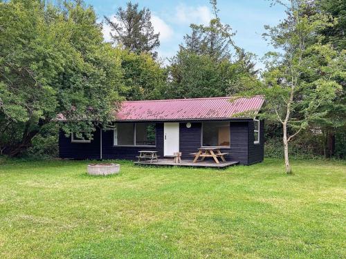 een zwart huis met een rood dak in een tuin bij 10 person holiday home in R m in Bolilmark