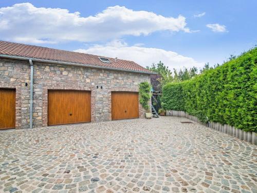 a brick building with two garage doors and a stone driveway at Enjoy a relaxing break for two and discover Durbuy in Biron