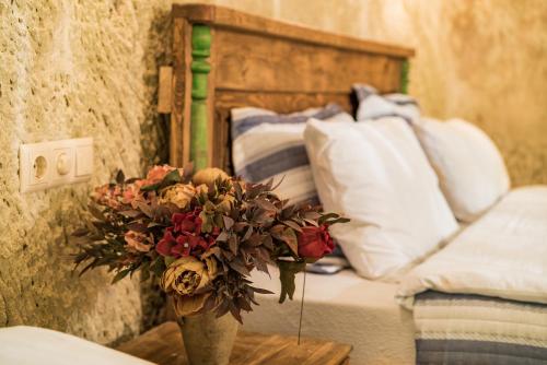 a vase with flowers on a table next to a bed at Atilla's Cave Hotel in Nevsehir
