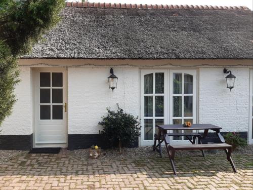 a white house with a picnic table in front of it at Bij de Vlaamse Schuur in Wagenberg