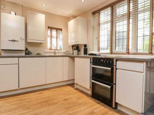 a kitchen with white cabinets and a black oven at Mayfield Cottage in Blackpool