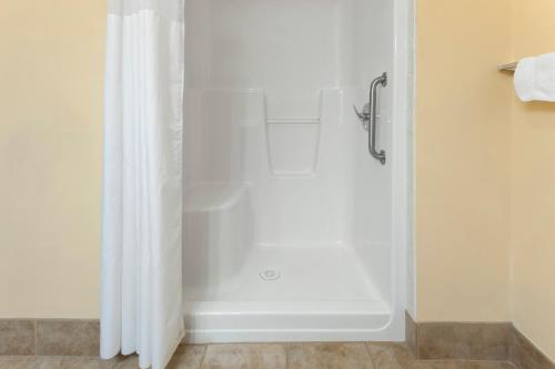 a shower with a white shower curtain in a bathroom at Super 8 by Wyndham Fort Saskatchewan in Fort Saskatchewan