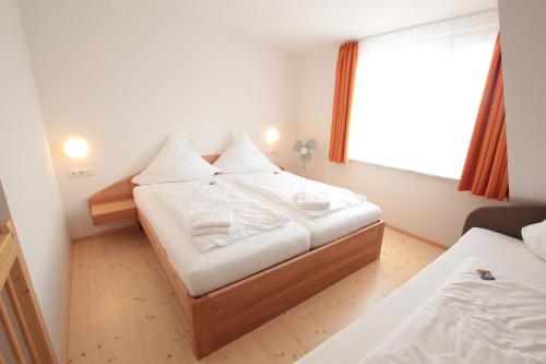 a bedroom with a bed with white sheets and a window at Hotel Sunnegässle in Rust