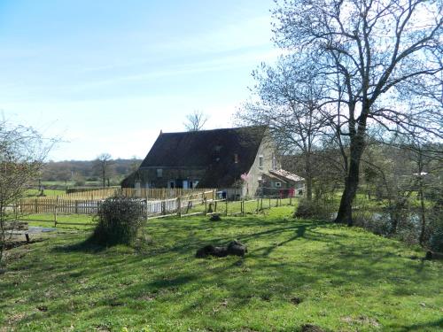 a barn in a field with a cow laying in the grass at Meublés de tourisme La Reserve in Saint-Pierre-les-Bois