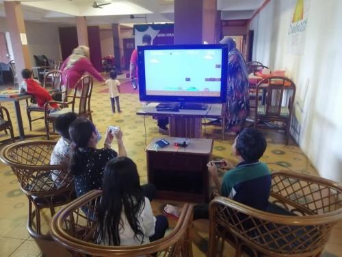 a group of children sitting in chairs watching a television at Mersing Merlin Inn in Mersing