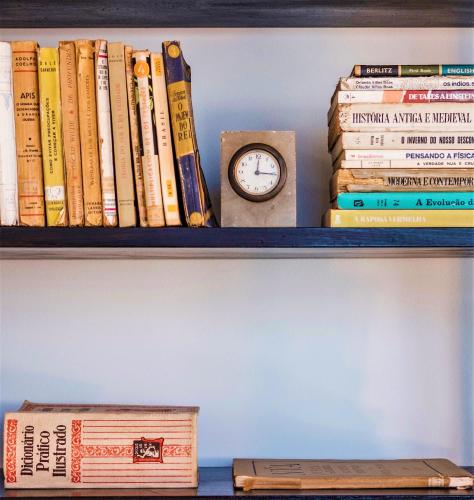 a shelf with books and a clock on it at BABhouse Casa da Colmeia - Coração do Douro in São João da Pesqueira