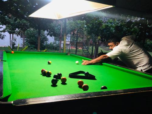 a man playing pool on a pool table at 1000 SILVERS -Farm Stay in Mysore