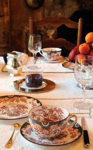 una mesa con platos y tazas y vasos. en Château de la Venerie, en Denicé