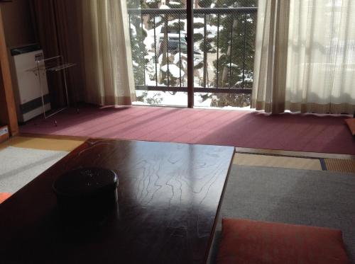 a living room with a table and a window at Lodge Matsuya in Nozawa Onsen