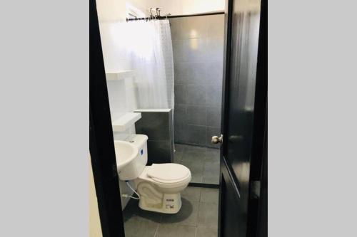 La salle de bains est pourvue d'une douche et de toilettes blanches. dans l'établissement Casa - Cabaña ELA en Coveñas, frente al mar, à Coveñas