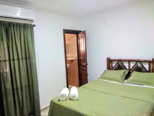 a bedroom with two beds with green sheets and shoes at Herard share apartamento in Punta Cana