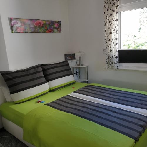 ein Schlafzimmer mit einem grün-blauen Bett und einem Fenster in der Unterkunft Ferienapartment MOHNBLUME in Eichwalde