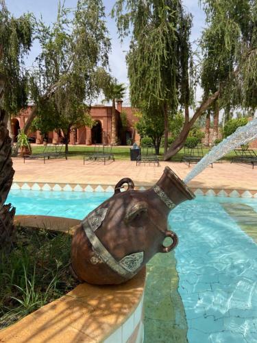 a statue of a water jug sitting next to a pool at LES JARDINS DE MARRAKECH in Marrakech