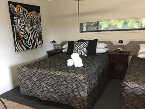 a white cat sitting on top of a bed in a bedroom at Golden Palms Motor Inn in Bundaberg