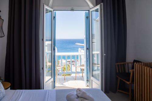 a bedroom with a door open to a balcony with the ocean at Harmony Boutique Hotel in Mýkonos City