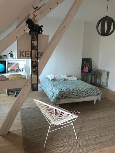 a bedroom with a bed and a chair in a attic at Chez leo in Marboué