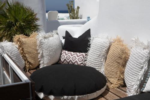 a couch with pillows on a balcony with a black ottoman at Harmony Boutique Hotel in Mýkonos City