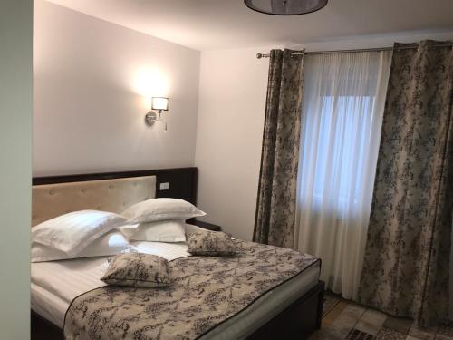 a bedroom with a bed with pillows and a window at Casa Pino in Braşov