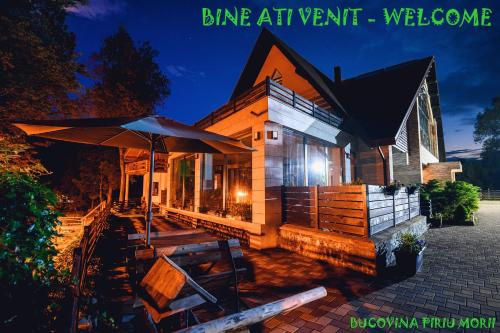 a house with an umbrella and a table and chairs at Pension Pîrîu' Morii in Gura Humorului
