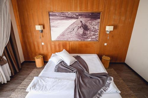 a bed in a room with a picture on the wall at Pension Pîrîu' Morii in Gura Humorului