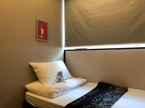 a teddy bear sitting on a pillow on a bed at Homy Inn North Point in Hong Kong