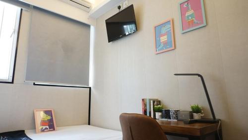 a room with a tv on a wall with a chair at Homy Inn North Point in Hong Kong