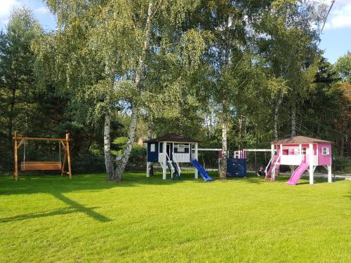 a group of playground equipment in a grass field at Leśna Osada przy Suntago Park in Krzyżówka