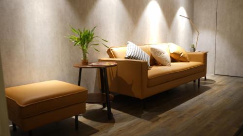a living room with a couch and a stool and a table at Homy Inn North Point in Hong Kong