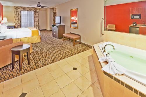 Habitación de hotel con cama extragrande y bañera en Holiday Inn Express Hotel & Suites Clinton, an IHG Hotel, en Clinton