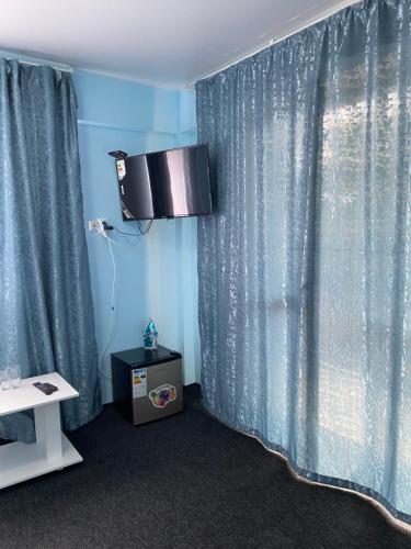 a room with a window with blue curtains at Пана in Almaty