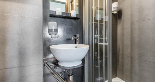 ein Badezimmer mit einem weißen Waschbecken an der Wand in der Unterkunft feRUS Hotel in Luzern