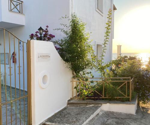 a white house with a gate and flowers at Nereides Apartments in Agios Gordios