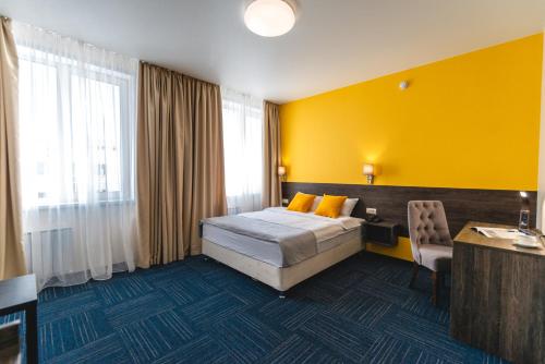 a bedroom with a bed and a desk and a yellow wall at Отель Авитель in Novosibirsk