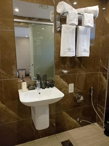 a bathroom with a sink and a mirror and towels at La Maison Royale South C in Nairobi