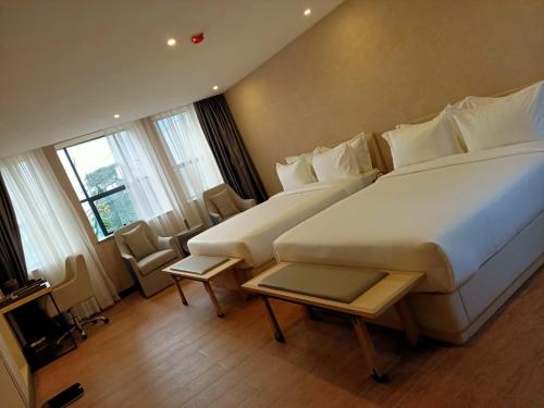 una habitación de hotel con una gran cama blanca y ventanas en La Maison Royale South C, en Nairobi