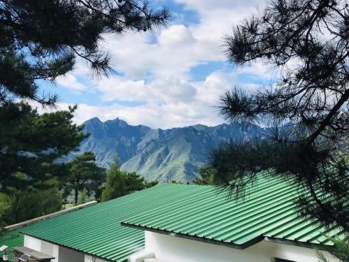 a green roof on a building with mountains in the background at Home of the Great Wall in Huairou