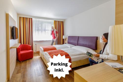 um quarto de hotel com uma cama e uma mulher sentada numa cadeira em Hotel Coop Tagungszentrum & Hotelpark im Grünen em Muttenz