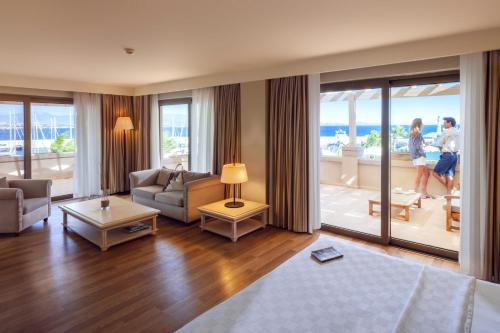 a living room with a bed and a balcony with the ocean at Yacht Club in Didim