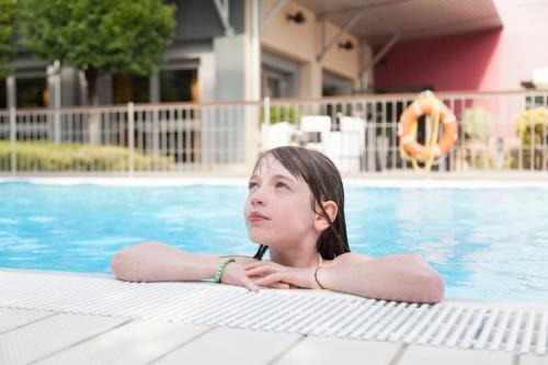 a young girl laying in a swimming pool at Novotel Brescia Due in Brescia