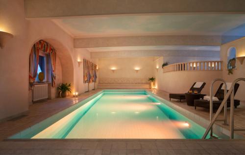 a large swimming pool in a room with a couch at Ringhotel Winzerhof in Rauenberg