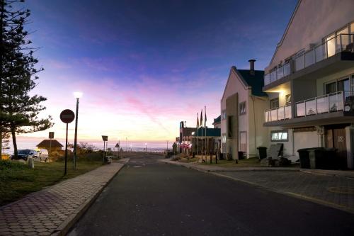 an empty street in front of a building with the ocean at The Point Hotel & Spa in Mossel Bay