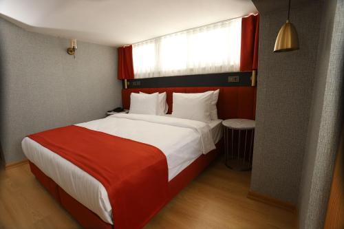 a bedroom with a large bed with a red and white blanket at My Garden Hotel in Istanbul