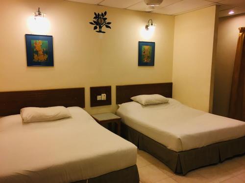 two beds in a hotel room with lights on the wall at Coastal Park Hotel in Melaka