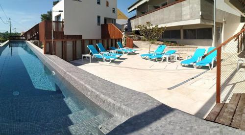 a swimming pool with blue lounge chairs next to a building at Albergaria da Tomásia in Aldeia do Meco