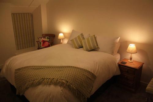 a bedroom with a large white bed with two lamps at Bojewyan Cottage, Sandy Beaches and Great walking in Penzance