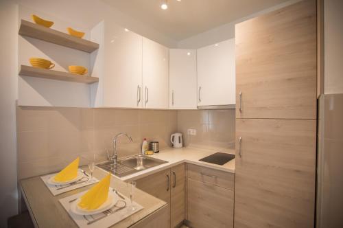 Una pequeña cocina con gabinetes blancos y un fregadero. en Jelena Apartment II, en Doboj