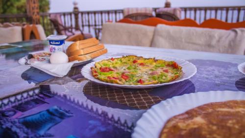 a table with a plate of pizza and bread on it at Ali Baba Hotel in Dahab