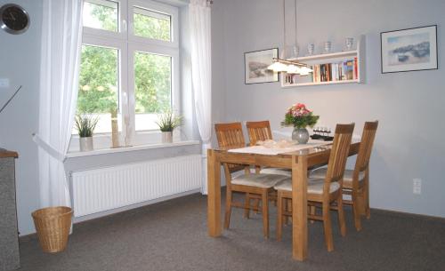 ein Esszimmer mit einem Tisch, Stühlen und einem Fenster in der Unterkunft Ferienwohnung Ilsebill in Husum