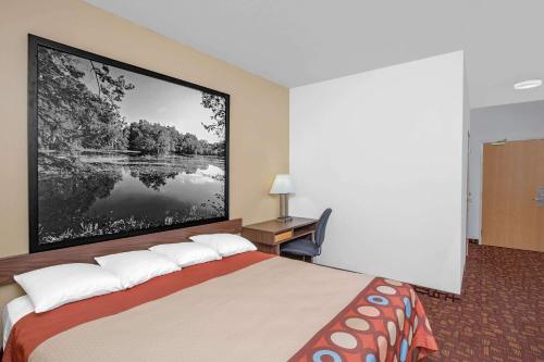 a hotel room with a bed with a large picture on the wall at Super 8 by Wyndham Three Rivers in Three Rivers